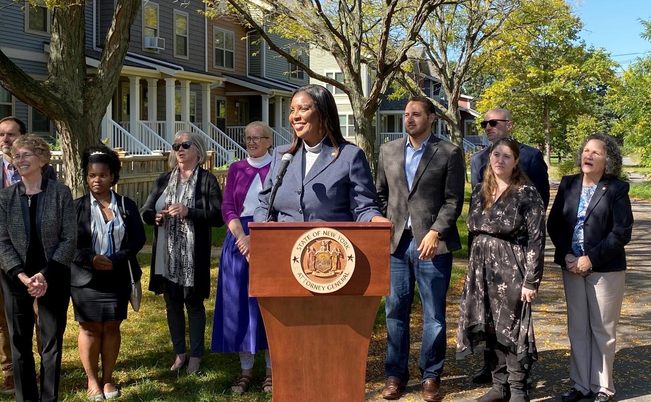 Attorney General James at podium surrounded by a group of people