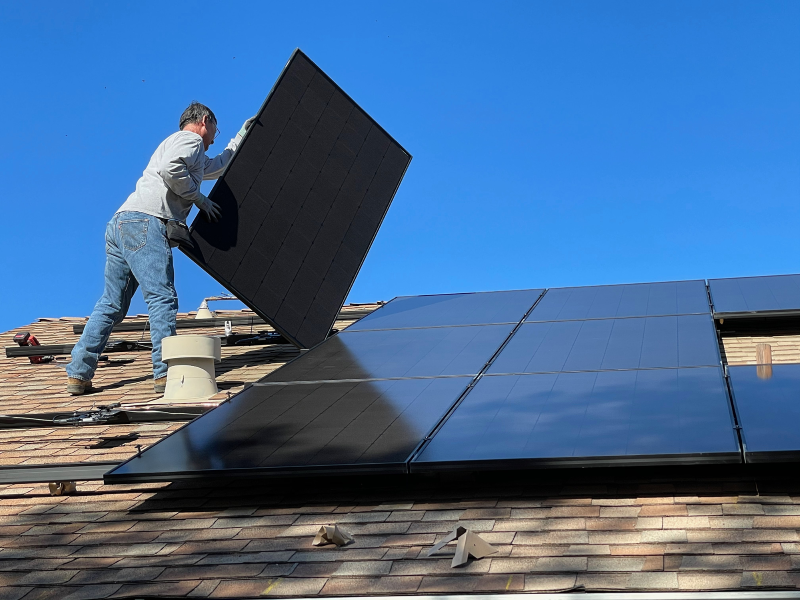 person installing solar panels on roof