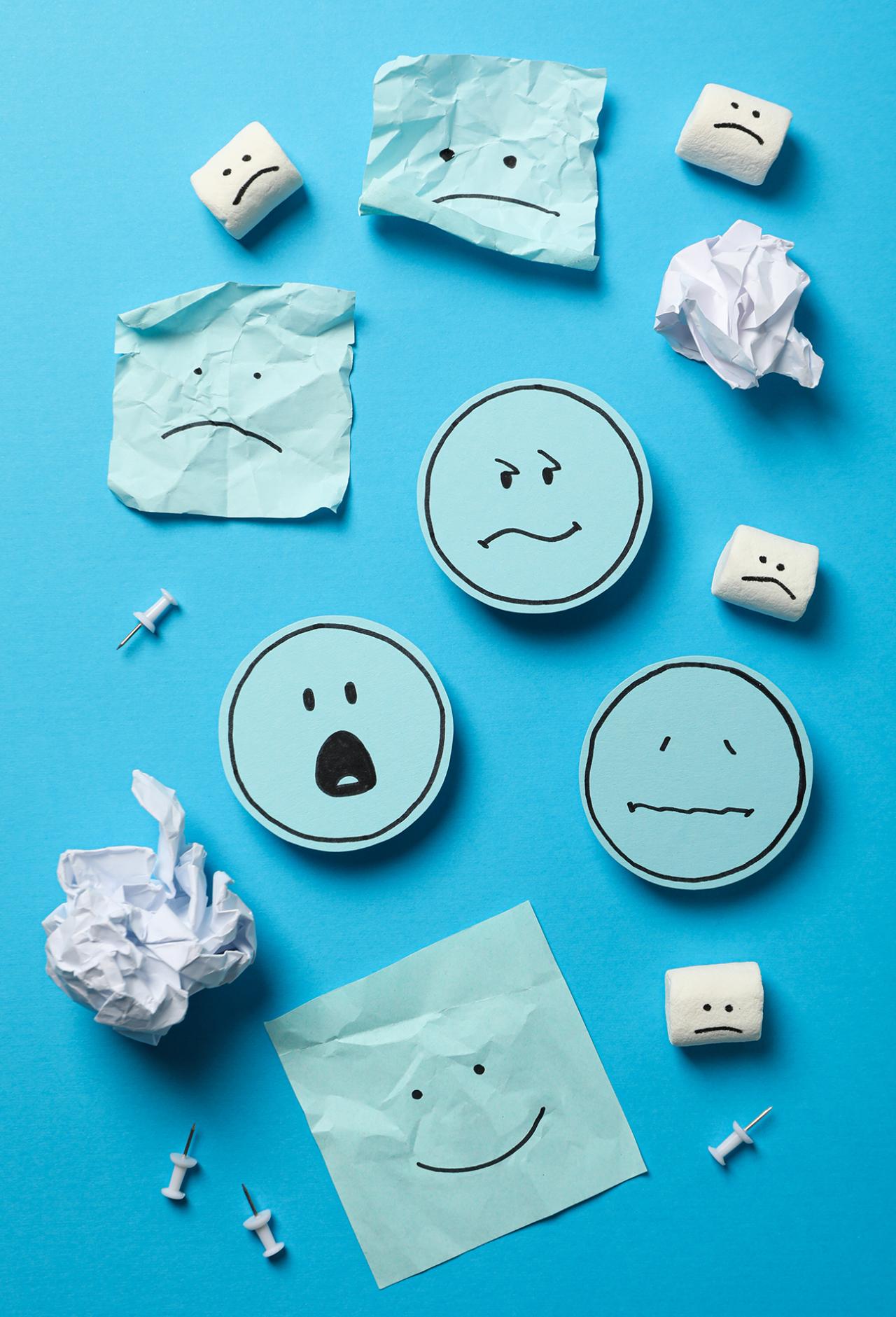 blue pieces of paper with different emotion faces - happy, sad, surprised